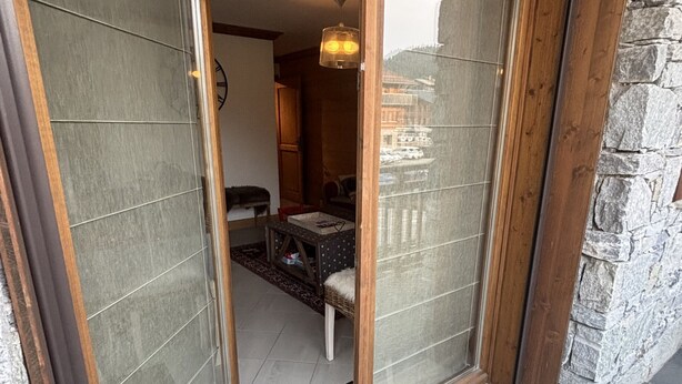A room with a wooden door, a small table, and a chair. - Comfortable apartment for 8 guests with private garage (Les Gets)