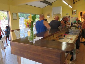 Un espace bar avec un comptoir en bois, des chaises et un vase rempli de fleurs.