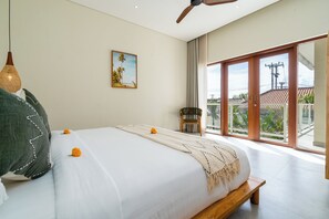 Ein Schlafzimmer mit einem Bett, einem Deckenventilator, einem Fenster mit Blick und einem Stuhl.
