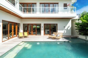 Uma casa moderna com piscina, deck de madeira e varanda com vista para a piscina.