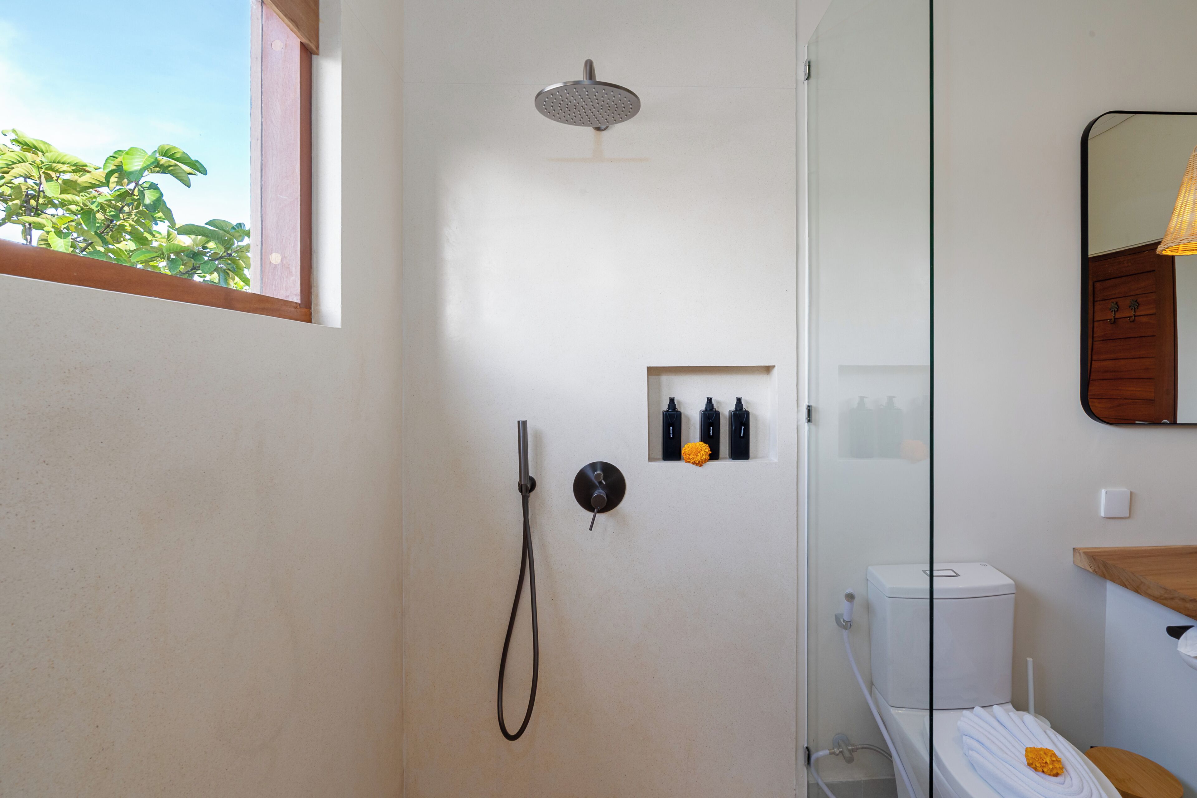 Un baño con ducha, inodoro y un pequeño estante con artículos de aseo.