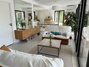 Ein modernes Wohnzimmer mit einer Couch, einem Couchtisch und einem Essbereich im Hintergrund.