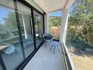 Ein Balkon mit Glasgeländer, einem kleinen Tisch und einem Stuhl.