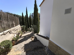 A courtyard with a gravel path, a white wall, and tall cypress trees. - Villa Cava, Calonge - Costa Brava (Calonge i Sant Antoni)