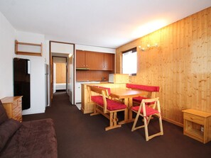 Ein kompaktes Zimmer mit Küchenzeile, einem Essbereich mit Holzmöbeln und einer kleinen Sitzecke.
