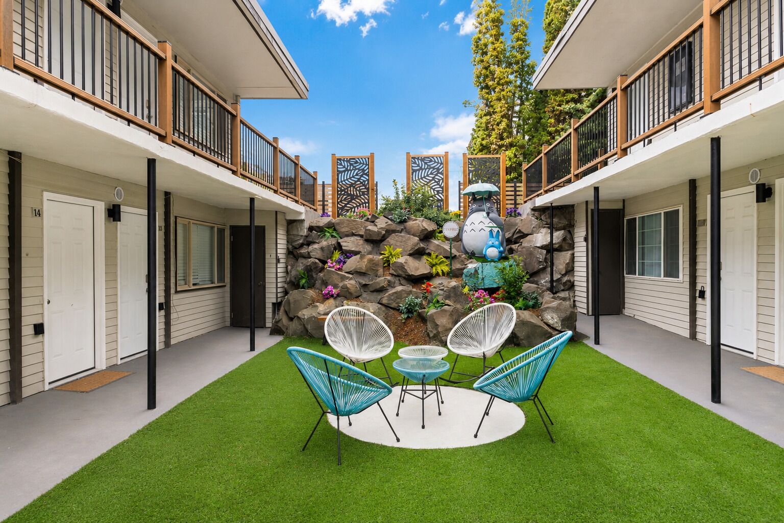 A courtyard with a rock wall, outdoor seating, and a decorative statue.