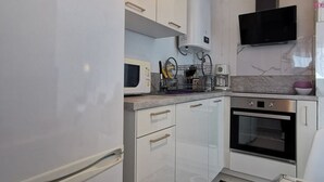 A compact kitchen with white cabinets, a microwave, a coffee maker, and a built-in oven. - Studio cabin, parking, near beach - 4 guests (Le Grau-du-Roi)