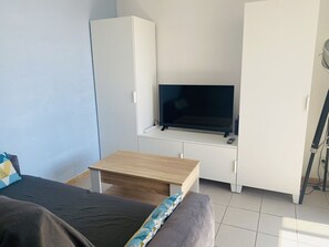 Ein Zimmer mit einem Bett, einem Schreibtisch, einem Fernseher und einem Kleiderschrank.