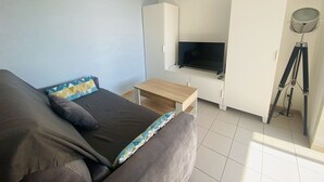 A bedroom with a bed, a TV, a desk, and a tripod. - Studio cabin, parking, near beach - 4 guests (Le Grau-du-Roi)
