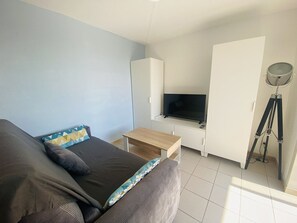 Ein Schlafzimmer mit einem Bett, einem Fernseher, einem Schreibtisch und einem Stativ.