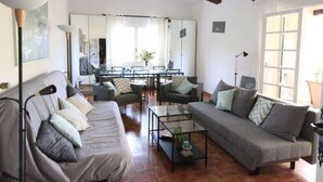 Una sala de estar con dos sofás, una mesa de centro, un comedor y un ventanal grande.