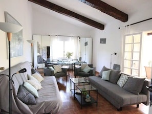 A living room with two sofas, a coffee table, a dining area, and a large window. - Lovely house with sea view - 8 guests (Cavalaire-sur-Mer)