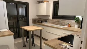 Una cocina compacta con una isla central, horno empotrado y microondas.