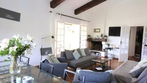 Una sala de estar moderna con una mesa de comedor de vidrio, sofás grises y una chimenea.
