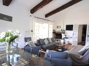 A modern living room with a glass dining table, grey sofas, and a fireplace. - Lovely house with sea view - 8 guests (Cavalaire-sur-Mer)