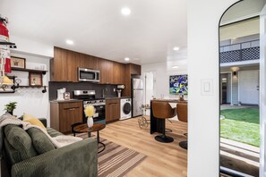 Une cuisine moderne avec des meubles en bois, un four à micro-ondes et un réfrigérateur. Il y a également un coin repas avec une table et des chaises.