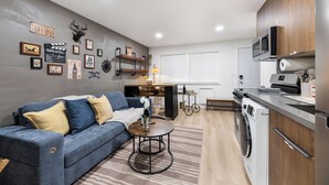 Eine moderne Küche mit Waschmaschine, einem Esstisch mit Stühlen, einer Couch und Wanddekorationen.
