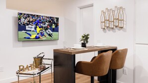 Ein moderner Essbereich mit Fernseher, Barwagen und Weinflaschen.