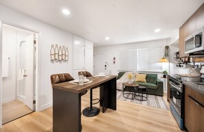 A modern kitchen with a dining area, a sofa, and a small table. - Modern Industrial Seattle Suite | Workspace + Kitchen (Seattle)