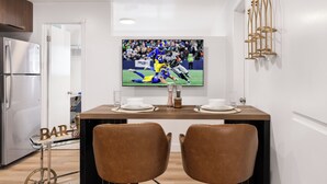 Eine moderne Küche mit Essbereich, einem an der Wand befestigten Fernseher und einem Barwagen.