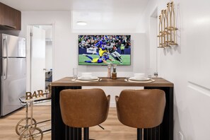 A modern kitchen with a dining area, a TV mounted on the wall, and a bar cart. - Modern Industrial Seattle Suite | Workspace + Kitchen (Seattle)
