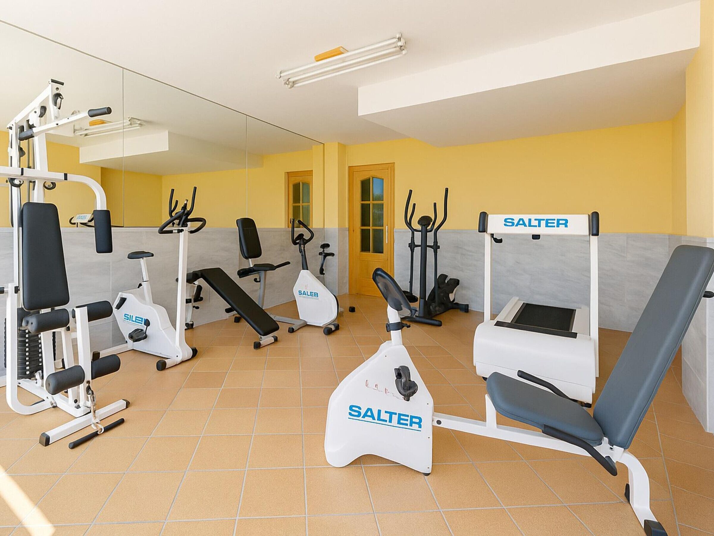 Et fitnesscenter med forskellig træningsudstyr, herunder løbebånd, spinningcykler og styrkemaskiner.