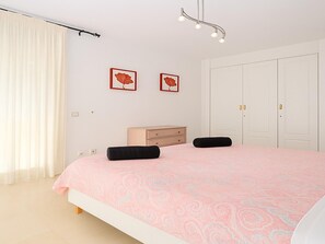 A bedroom with a bed, two pillows, a dresser, a nightstand, a ceiling light, and two framed pictures on the wall. - Elegant 2-bedroom apartment with terrace in Estepona (Estepona)