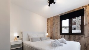 Ein Schlafzimmer mit Bett, Nachttischen, einem Fenster mit Aussicht und einem Deckenventilator.