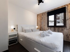 Ein Schlafzimmer mit Bett, Nachttischen, einem Fenster mit Aussicht und einem Deckenventilator.