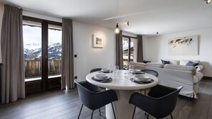 Ein moderner Essbereich mit einem runden Tisch, schwarzen Stühlen und Bergblick durch große Fenster.