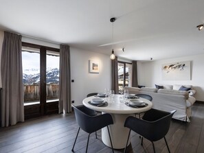 Ein moderner Essbereich mit einem runden Tisch, schwarzen Stühlen und Bergblick durch große Fenster.