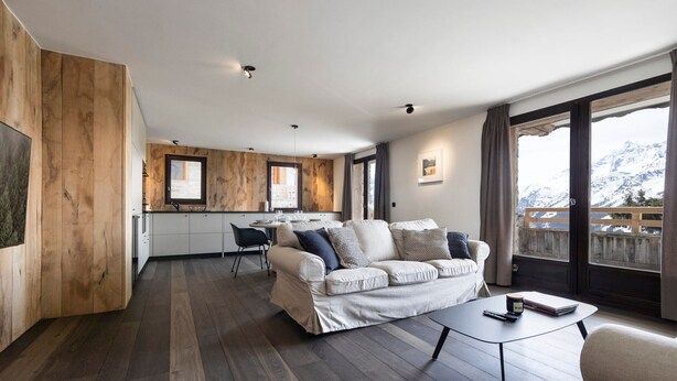 Ein modernes Wohnzimmer mit einer Couch, einem Couchtisch und Blick auf einen Berg.