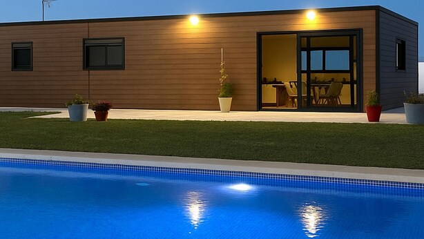 Um edifício moderno com piscina, plantas em vasos e área de pátio.
