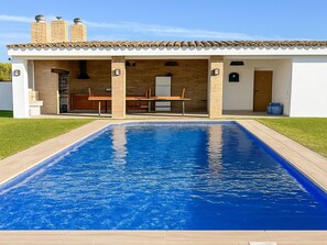 Ein modernes Haus mit Swimmingpool, einer Terrasse und Gartenmöbeln sowie einem Ziegelkamin.