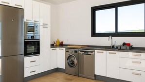 Cozinha moderna com eletrodomésticos de aço inoxidável, forno embutido, micro-ondas e máquina de lavar louça, além de uma janela sobre a pia.