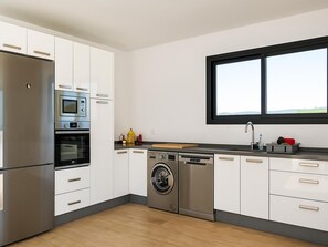 Eine moderne Küche mit Edelstahlgeräten, inklusive Backofen, Mikrowelle und Geschirrspüler, sowie ein Fenster über der Spüle.