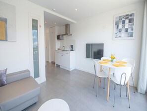 A modern apartment with a living area, a dining table with chairs, a kitchen, and a TV mounted on the wall. - Renovated Apartment in Marbella with Pool (Marbella)