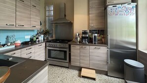 Une cuisine moderne avec des meubles en bois, une cuisinière en acier inoxydable, un réfrigérateur et une machine à café.
