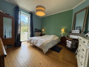A bedroom with a bed, a dresser, a mirror, a window with curtains, and a door. - Large typical Bauloise villa - 12 guests (La Baule)