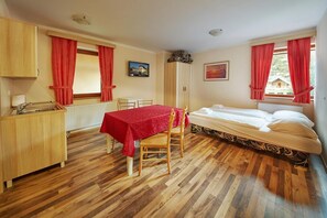 A room with a bed, a table with a red tablecloth, a wooden cabinet, and a radiator. - Garni Hotel Rute (Kranjska Gora)
