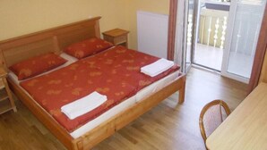 Un dormitorio con cama de madera, una mesita de noche, una silla y vistas al exterior a través de un ventanal.