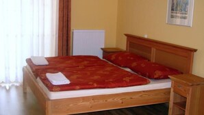 Una cama individual con cabecera de madera, una colcha roja y dos almohadas.