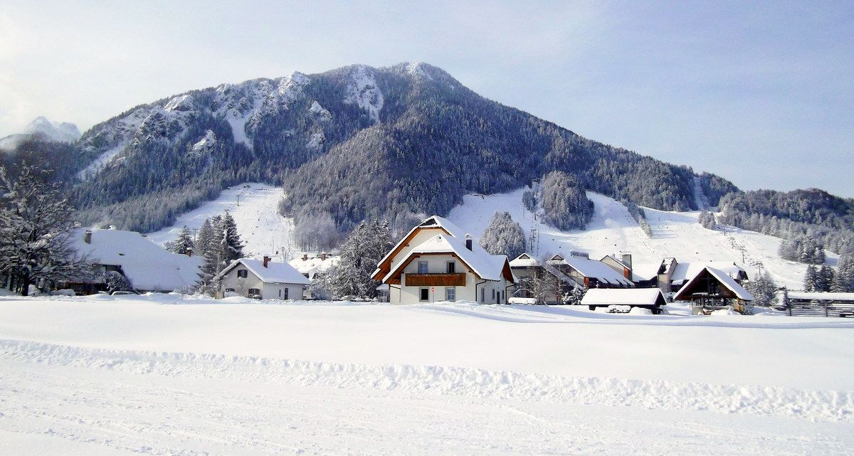 Un paysage montagneux enneigé, avec une rangée de bâtiments de style chalet traditionnel.