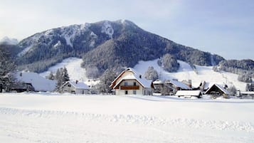 Paisagem montanhosa coberta de neve com uma fileira de edifícios em estilo chalé.