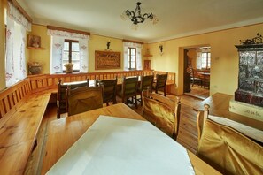 A dining area with wooden benches and chairs, a chandelier, and a view of the dining room through a window. - Garni Hotel Rute (Kranjska Gora)
