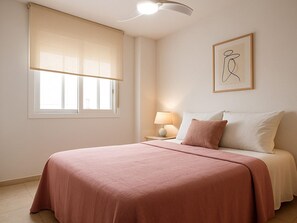 A bedroom with a bed, a window with blinds, a bedside lamp, and a framed picture on the wall. - Bright apartment in Estepona with balcony and private parking (Estepona)