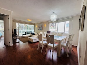 A spacious living area with a dining table, chairs, a sofa, and a chandelier. - Departamento en Santo domingo Tricao (Santo Domingo)