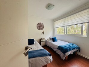 A bedroom with two beds, a window, a wall clock, and a door. - Departamento en Santo domingo Tricao (Santo Domingo)