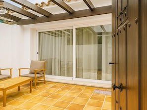 Ein Zimmer mit Schiebetür, einer Holzbank, einem Stuhl und einem Fliesenboden.