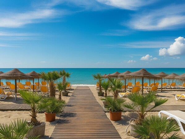 A beach with a wooden walkway leading to the sea, surrounded by sun loungers and thatched umbrellas. - Neptuno Apartment in Estepona, 3 bedrooms, air conditioning (Estepona)